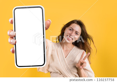 Happy young woman in casual show peace sign and phone Happy young woman in casual show peace sign and phone 110237758