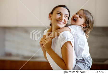 Laughing child embracing her joyful mother while they playing together at home 110237769