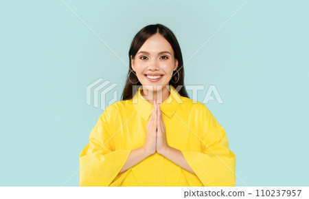 Positive young brunette woman holding hands in namaste gesture 110237957