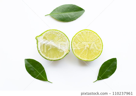 Ripe limes with green leaves on white. 110237961