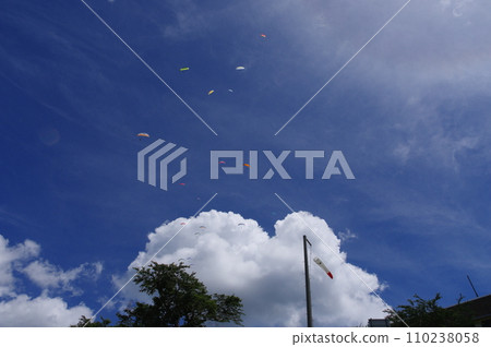 White clouds floating in the blue sky and paragliders dancing in the sky 110238058