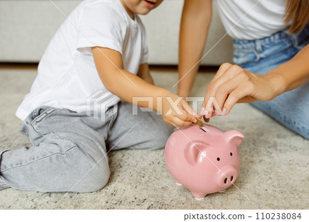 Family Savings. Mother And Daughter Inserting Coins To Piggy Bank At Home Family Savings. Mother And Daughter Inserting Coins To Piggy Bank At Home 110238084