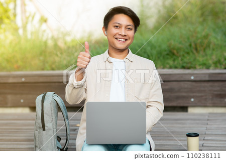 Smiling chinese guy independent contractor working at park Smiling chinese guy independent contractor working at park 110238111