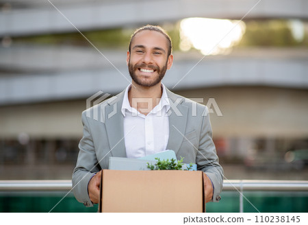 Young man in suit carrying box of office supplies and personal belongings 110238145