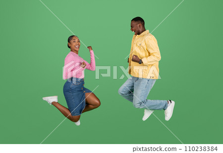 Emotional young african american couple jumping up and clenching fists Emotional young african american couple jumping up and clenching fists 110238384