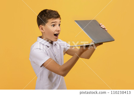 Amazed teen boy opening laptop in his hands 110238413