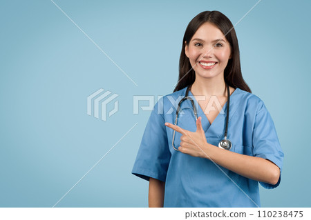 Confident nurse pointing to the side at free space, wearing scrubs Confident nurse pointing to the side at free space, wearing scrubs 110238475