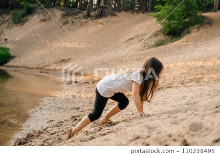 Energetic girl climbing up small hill on sandy beach near river. Little athlete actively spend time close to water. Energetic girl climbing up small hill on sandy beach near river. Little athlete actively spend time close to water. 110238495