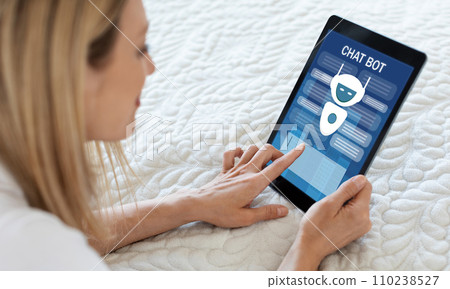 Blonde woman using chatbot on digital tablet, home interior 110238527