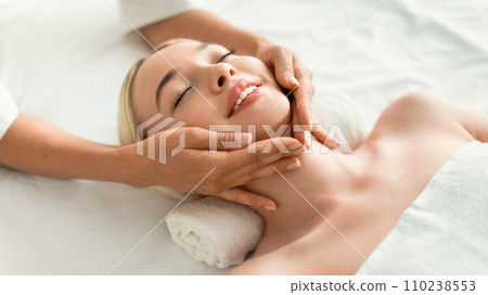 Young Blonde Woman Enjoying Relaxing Massage Lying On Bed Indoors Young Blonde Woman Enjoying Relaxing Massage Lying On Bed Indoors 110238553