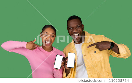 Cheerful Black Couple Pointing At Big Blank Smartphone Cheerful Black Couple Pointing At Big Blank Smartphone 110238724