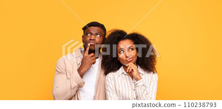 Pensive black couple in casual wear on yellow backdrop Pensive black couple in casual wear on yellow backdrop 110238793