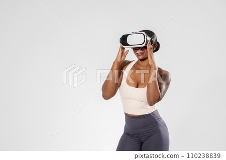 black woman in activewear immersed in VR exercise, white backdrop 110238839