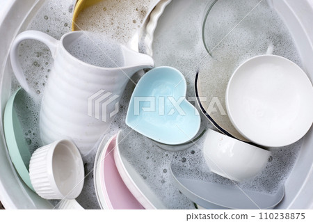 Dishes and bowls in water and bubbles of dishwashing liquid. Kitchen work 110238875