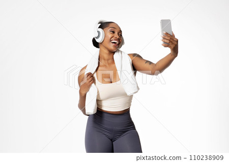 african lady in sportswear and headphones making video call, studio 110238909
