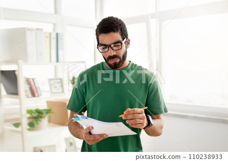 Concentrated man with glasses and a beard, wearing a green t-shirt 110238933