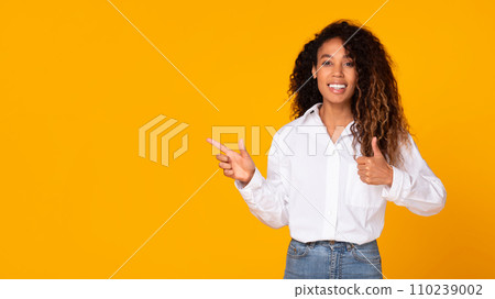 Excited African American Gesturing Thumbs Up Woman Pointing Aside, Studio 110239002