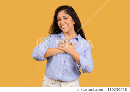 Content young woman with wavy hair, hands crossed over chest, smiling with gratitude Content young woman with wavy hair, hands crossed over chest, smiling with gratitude 110239018