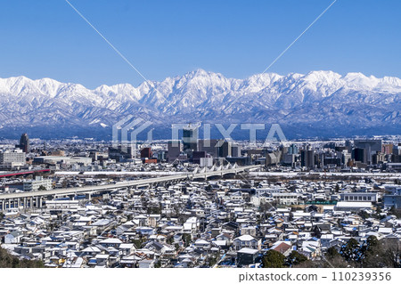 Hokuriku Shinkansen running, snowy Toyama city and Tsurugidake Tateyama mountain range 110239356