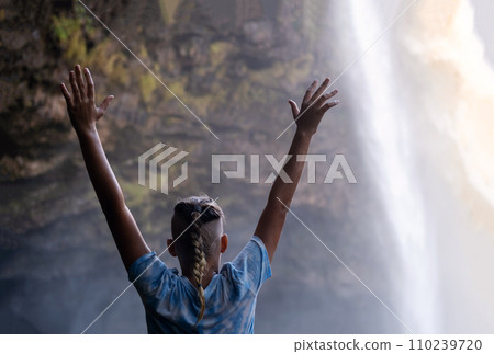 Teenage boy hands up and looking at the waterfall cascades before him. Teenage boy hands up and looking at the waterfall cascades before him. 110239720