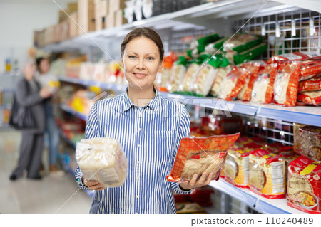 Woman in supermarket buys daily groceries, pasta Chinese noodles Woman in supermarket buys daily groceries, pasta Chinese noodles 110240489