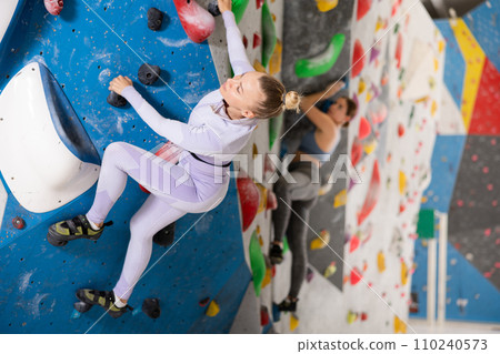 Adult woman practicing rock climbing on climbing wall 110240573