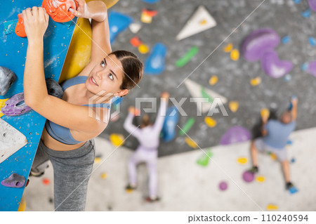 Young woman practicing rock climbing on climbing wall Young woman practicing rock climbing on climbing wall 110240594