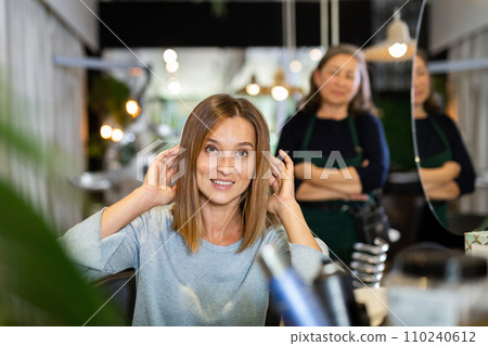 Delighted female client sitting in hairdressing chair after haircut Delighted female client sitting in hairdressing chair after haircut 110240612