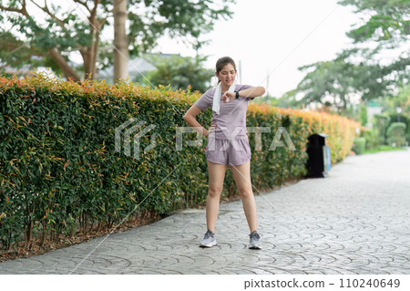 Sport young woman looking at smartwatch on her wrist, tracking fitness activity during training outdoors 110240649