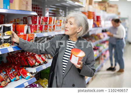 Senior woman in supermarket buys instant fast food in bowl 110240657