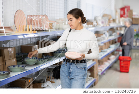 Interested young girl choosing ceramic Asian style plates in store Interested young girl choosing ceramic Asian style plates in store 110240729