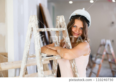 Woman in dress standing at stepladder in building site Woman in dress standing at stepladder in building site 110240730
