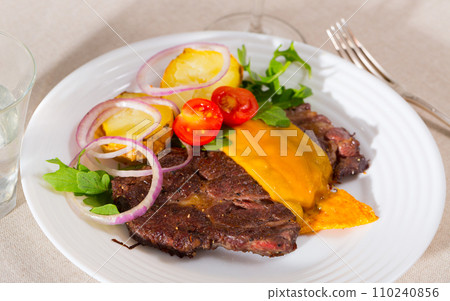Well-cooked beef steak with cheese and baked potatoes served at plate 110240856