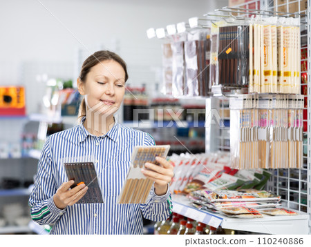 Woman customer chooses Chinese chopsticks in oriental goods department. Woman customer chooses Chinese chopsticks in oriental goods department. 110240886