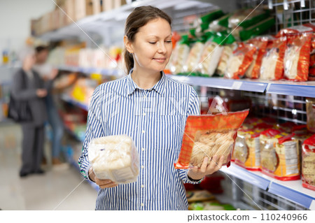 Woman in supermarket buys daily groceries, pasta Chinese noodles Woman in supermarket buys daily groceries, pasta Chinese noodles 110240966