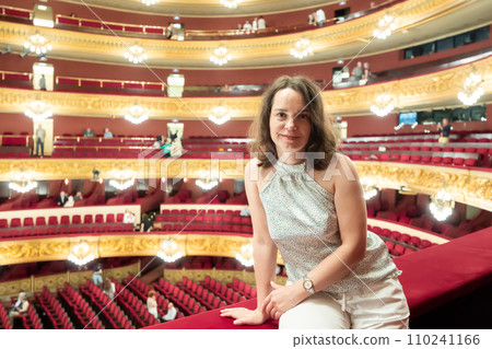 Woman after watching performance poses in auditorium balcony of opera theater 110241166