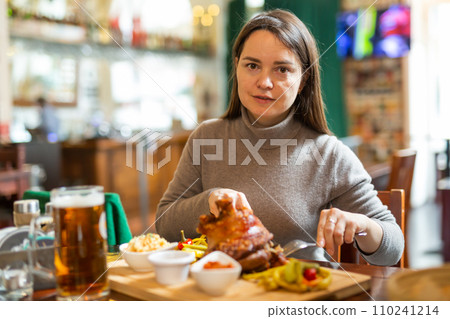 Female traveler tasting fried pork knuckle with beer in cafe 110241214
