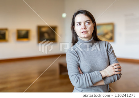 Female art lover viewing collection of paintings in art museum 110241275