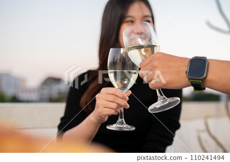 A beautiful woman are toasting champagne with her boyfriend, having a date night on a rooftop bar . A beautiful woman are toasting champagne with her boyfriend, having a date night on a rooftop bar . 110241494