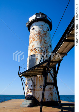 Sunlit Aged Lighthouse in Empire, Michigan Overlooking Calm Sea 110243804