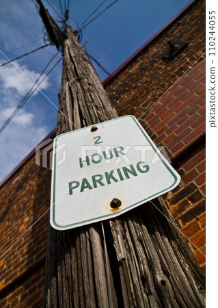Weathered Parking Sign on Utility Pole against Red Brick in Urban Setting Weathered Parking Sign on Utility Pole against Red Brick in Urban Setting 110244055