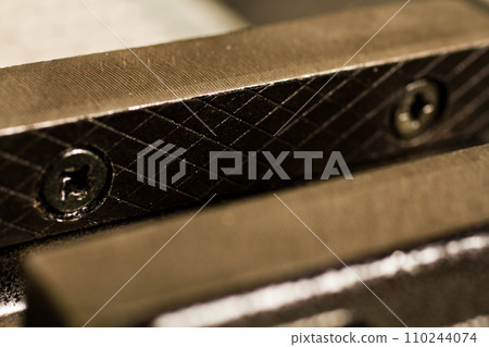 Detail of Metal Part with bolts and diamond pattern in yellow light Close-Up Detail of Metal Part with bolts and diamond pattern in yellow light Close-Up 110244074