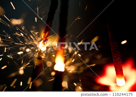 Close-up of Sparkling Embers from Handheld Sparklers in Dark Background Close-up of Sparkling Embers from Handheld Sparklers in Dark Background 110244175
