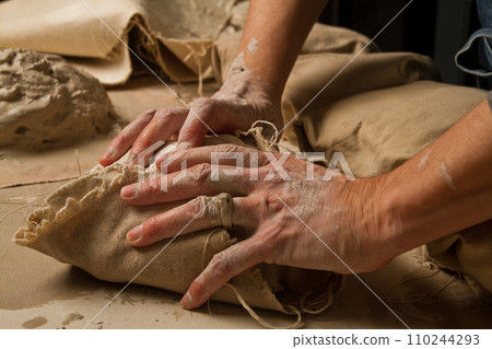 Artisan Working Wet Clay Wrapped in Beige Canvas on Crafting Table Artisan Working Wet Clay Wrapped in Beige Canvas on Crafting Table 110244293