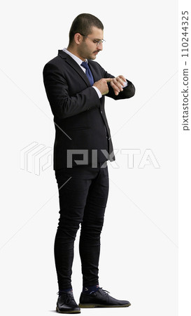 young man in full growth. isolated on white background looking at wristwatch 110244325