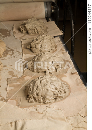 Ready for Craft: Wet Clay on Conveyor Belt in Pottery Workshop Ready for Craft: Wet Clay on Conveyor Belt in Pottery Workshop 110244327