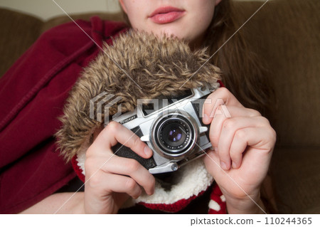 Vintage Film Camera Covered in Winter Hat in Hands of Young Woman Vintage Film Camera Covered in Winter Hat in Hands of Young Woman 110244365