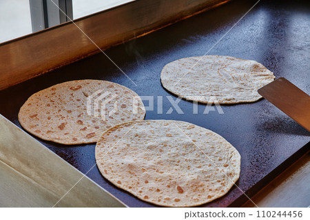 Traditional Flour Tortillas Cooking on Seasoned Griddle in Taqueria Traditional Flour Tortillas Cooking on Seasoned Griddle in Taqueria 110244456