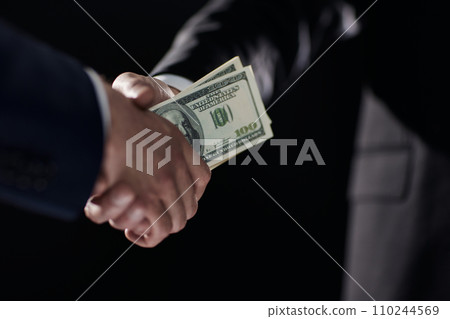 Handshake with the transfer of money on a black background Handshake with the transfer of money on a black background 110244569