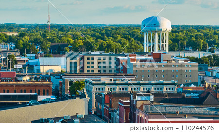Downtown Muncie, IN aerial of city buildings leading to American Water tower and green trees 110244576